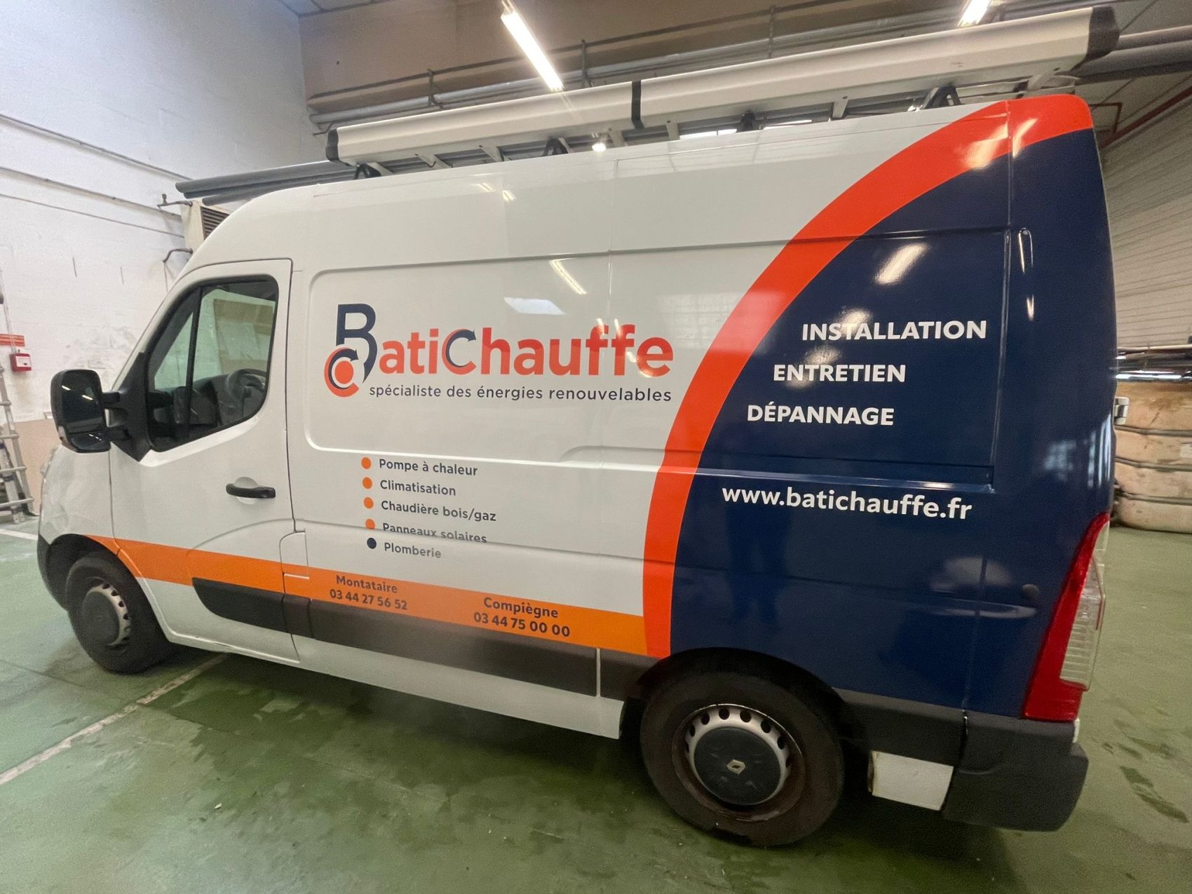 Fourgon BatiChauffe avec marquage orange et bleu dans l’atelier.