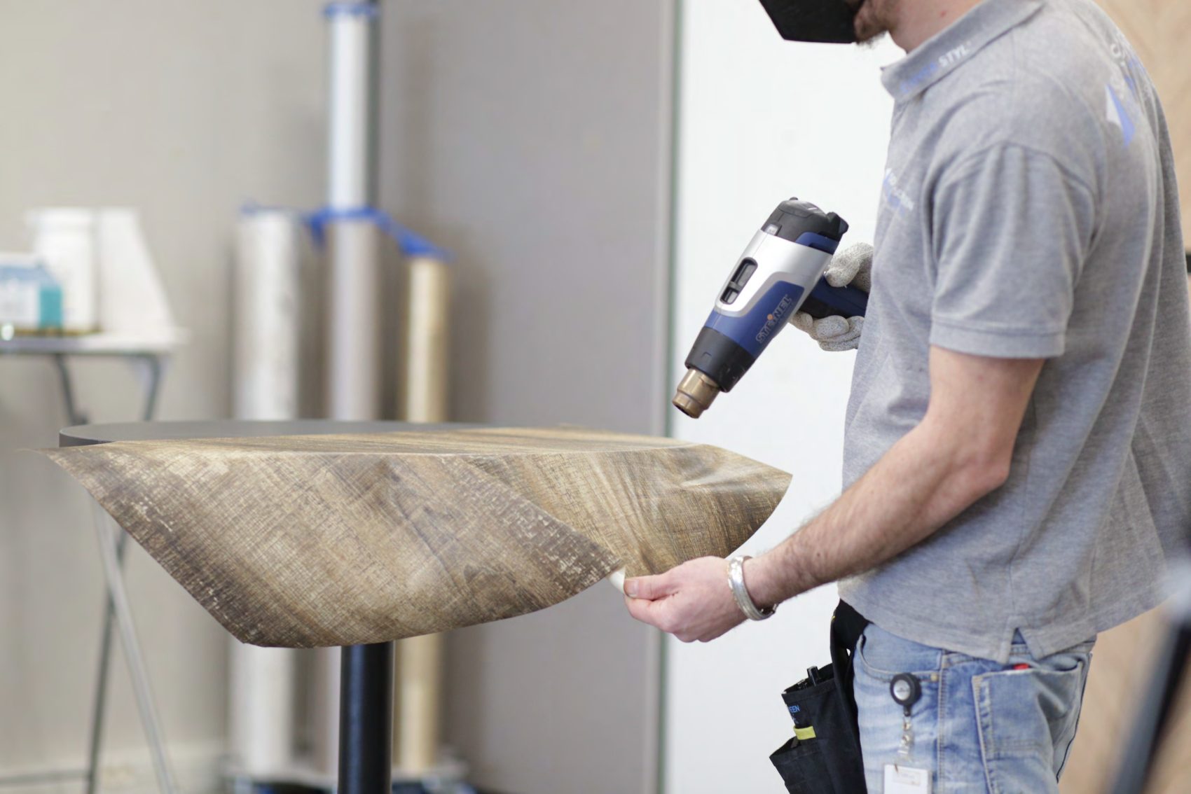 Pose d’un film adhésif décoratif effet bois sur le plateau et le bord d’une table